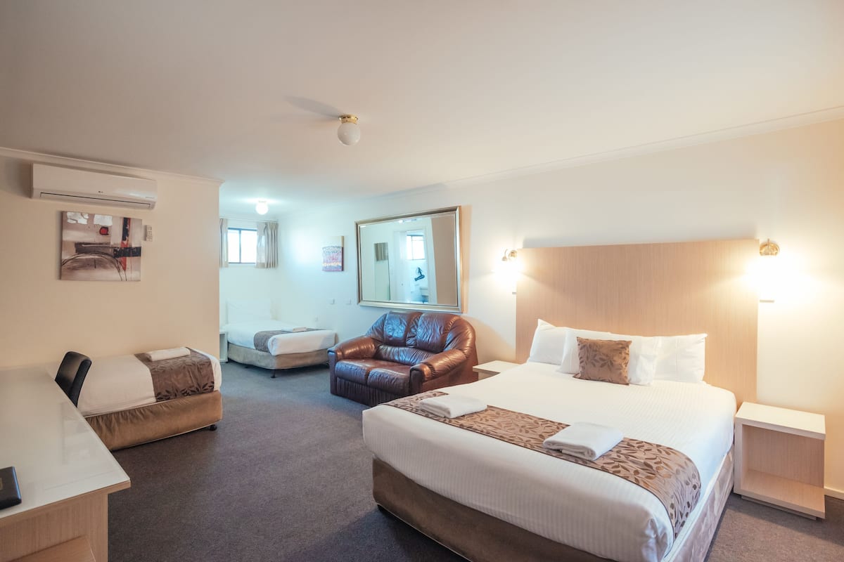 A hotel room with a large bed, a desk, a chair, and a mirror.