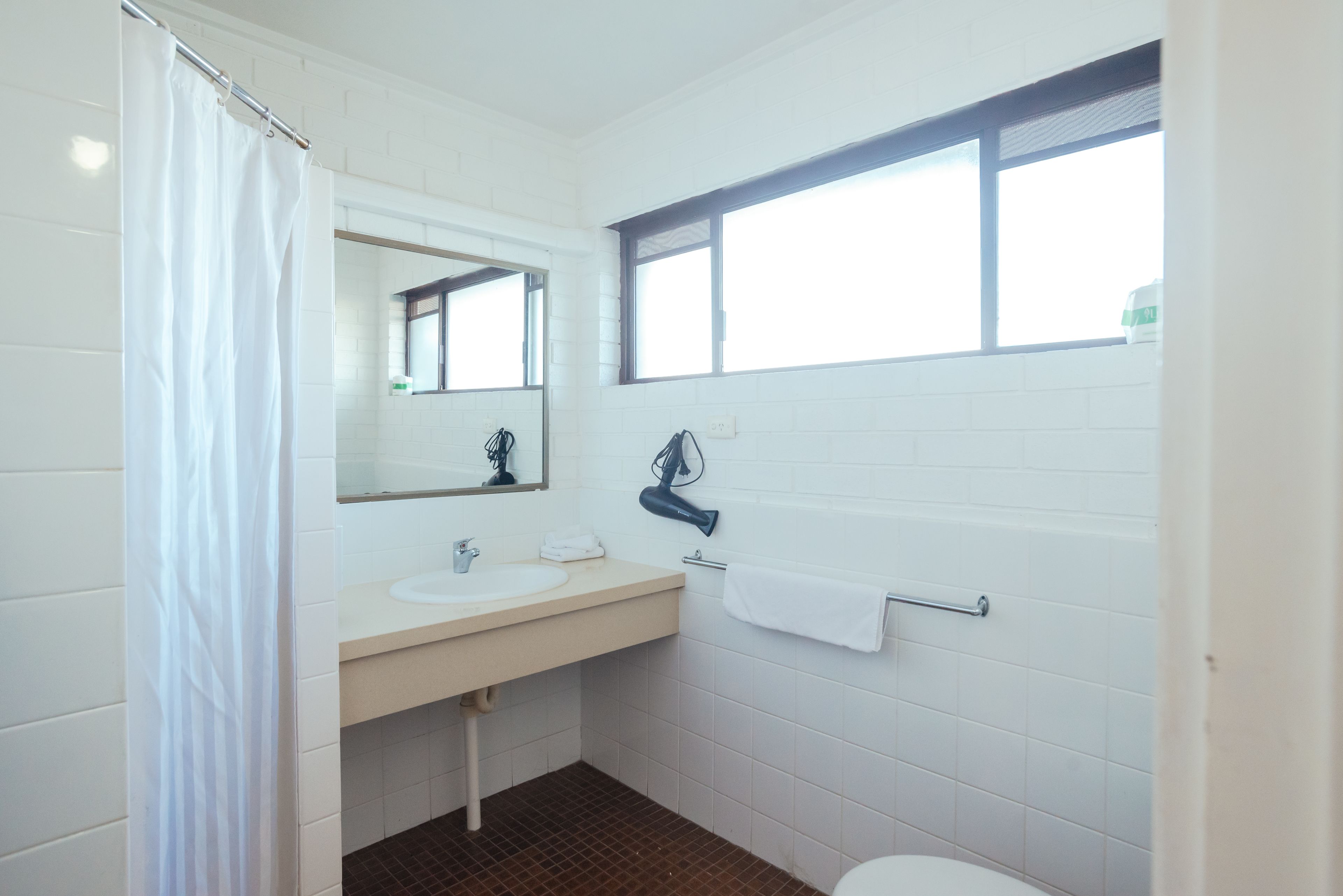 A bathroom with a white sink, mirror, and towel rack.