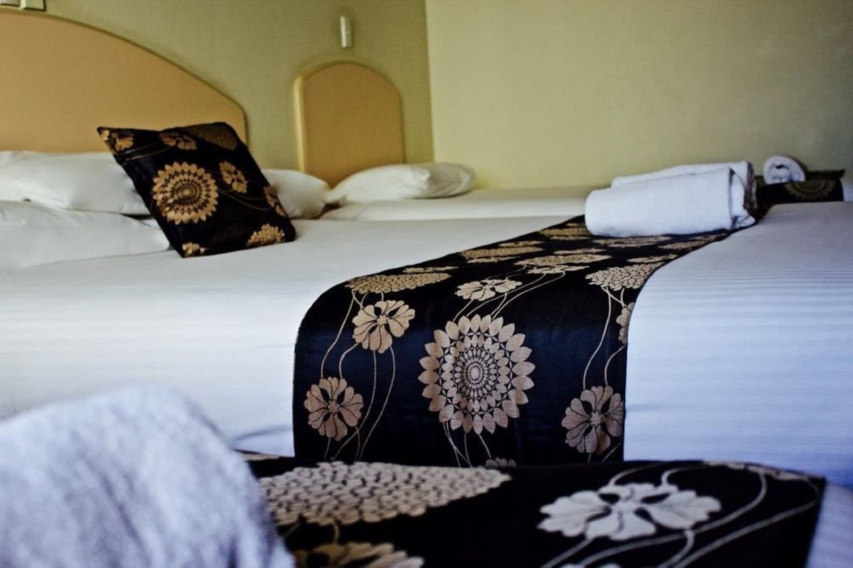 A hotel room with a bed, pillows, and a neatly folded towel.