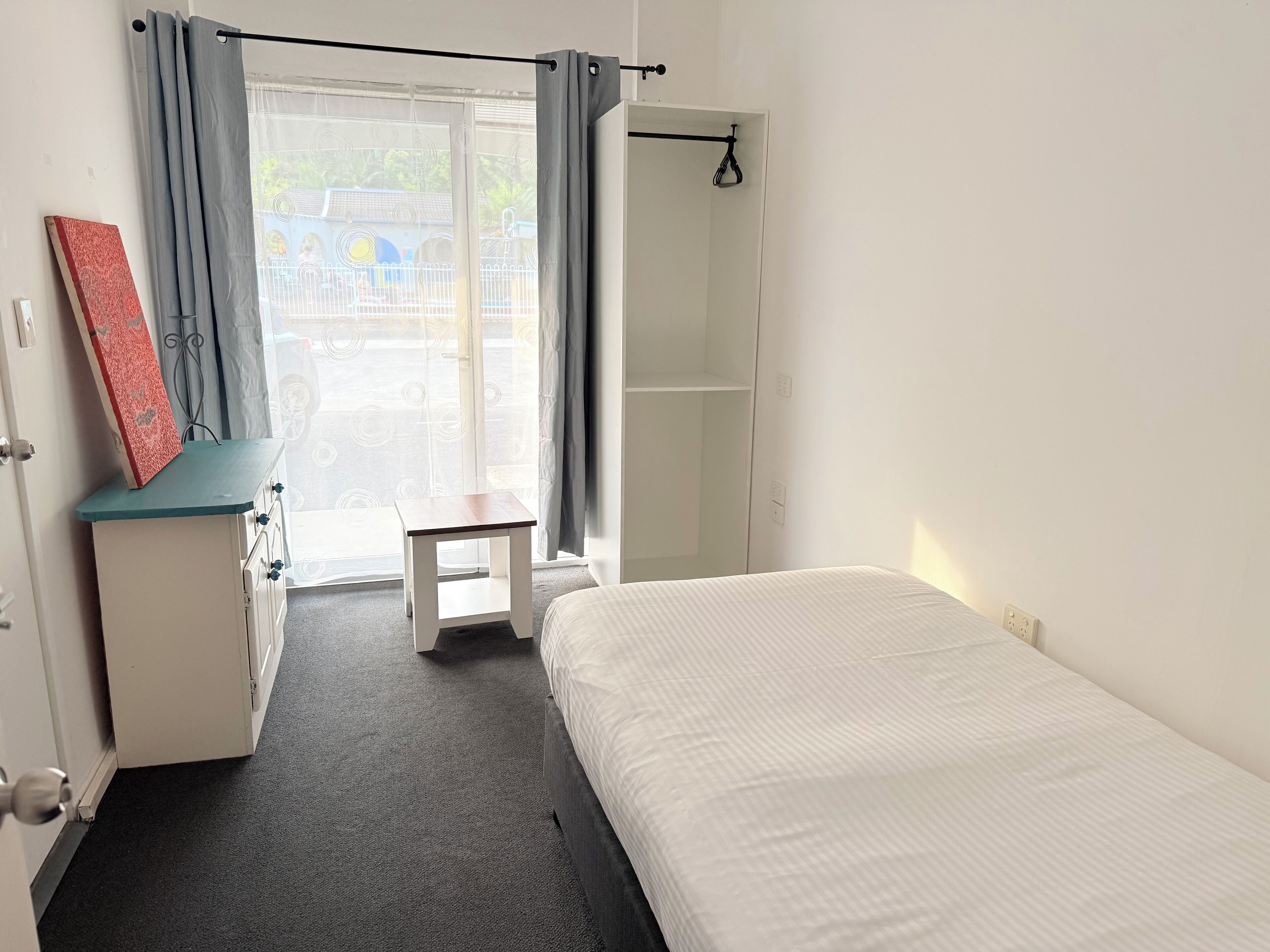 A room with a bed, a desk, a chair, and a wardrobe.