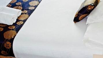 Habitación de hotel con dos camas, cada una con una colcha azul estampada con flores y sábanas blancas.