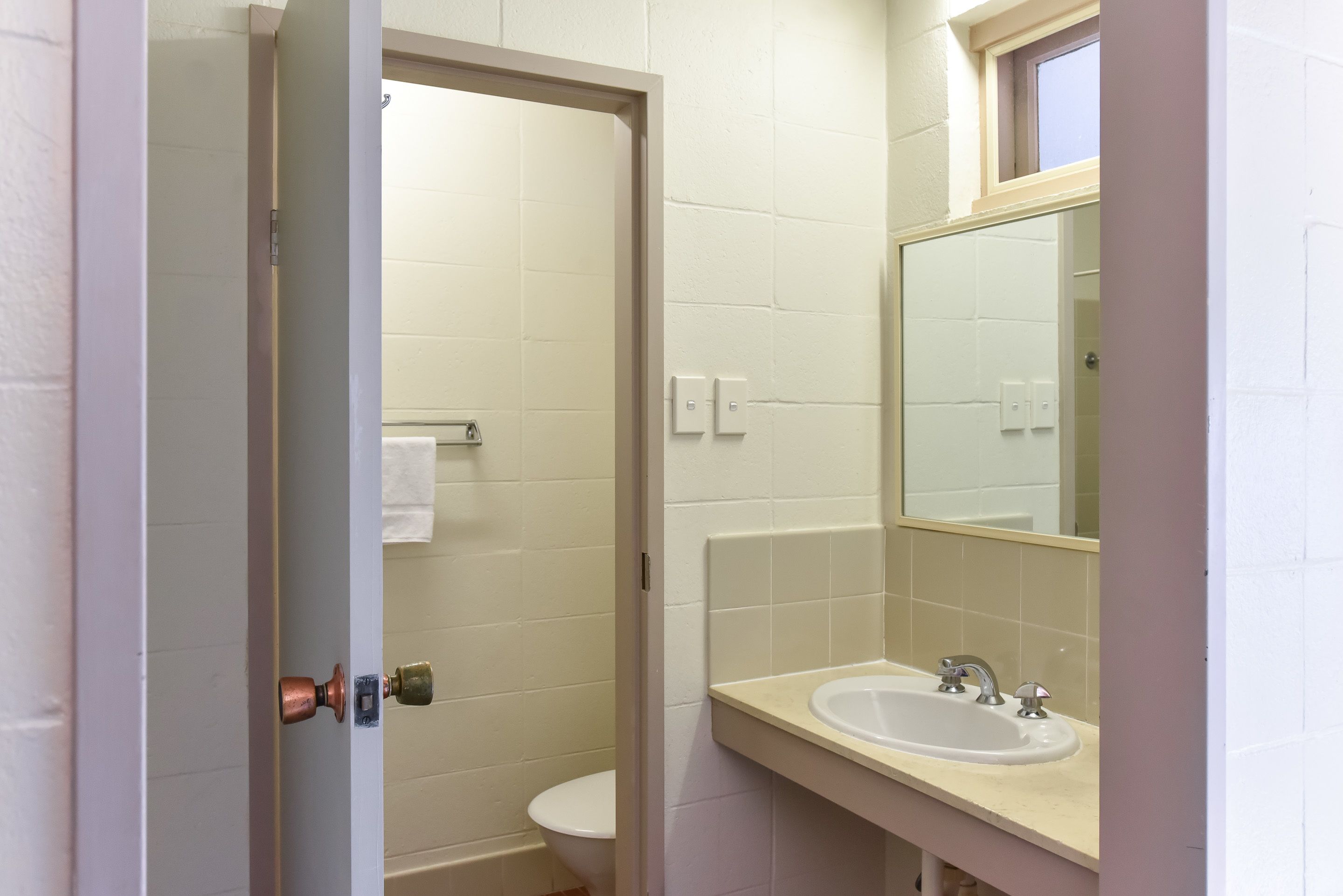 Une salle de bain avec des toilettes, un lavabo et un miroir.