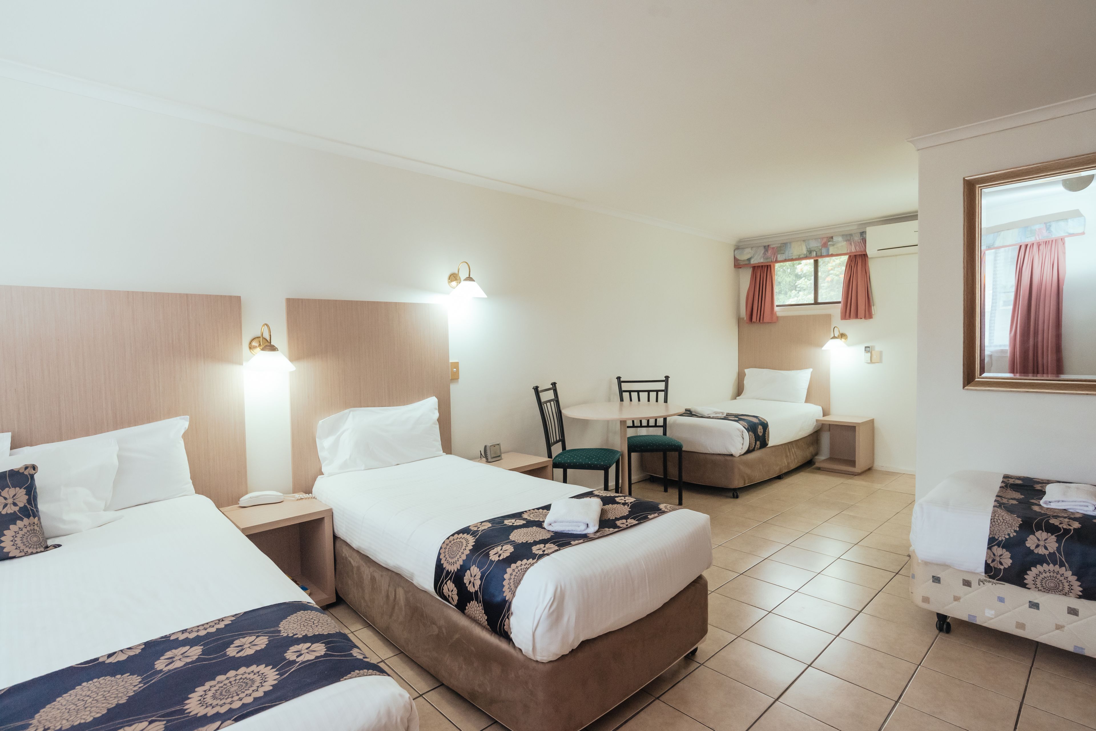 A hotel room with two beds, a small dining table, and a separate seating area.