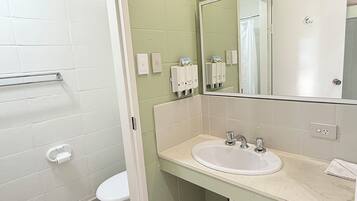 Un baño con inodoro blanco, lavamanos con espejo y un perchero para toallas.