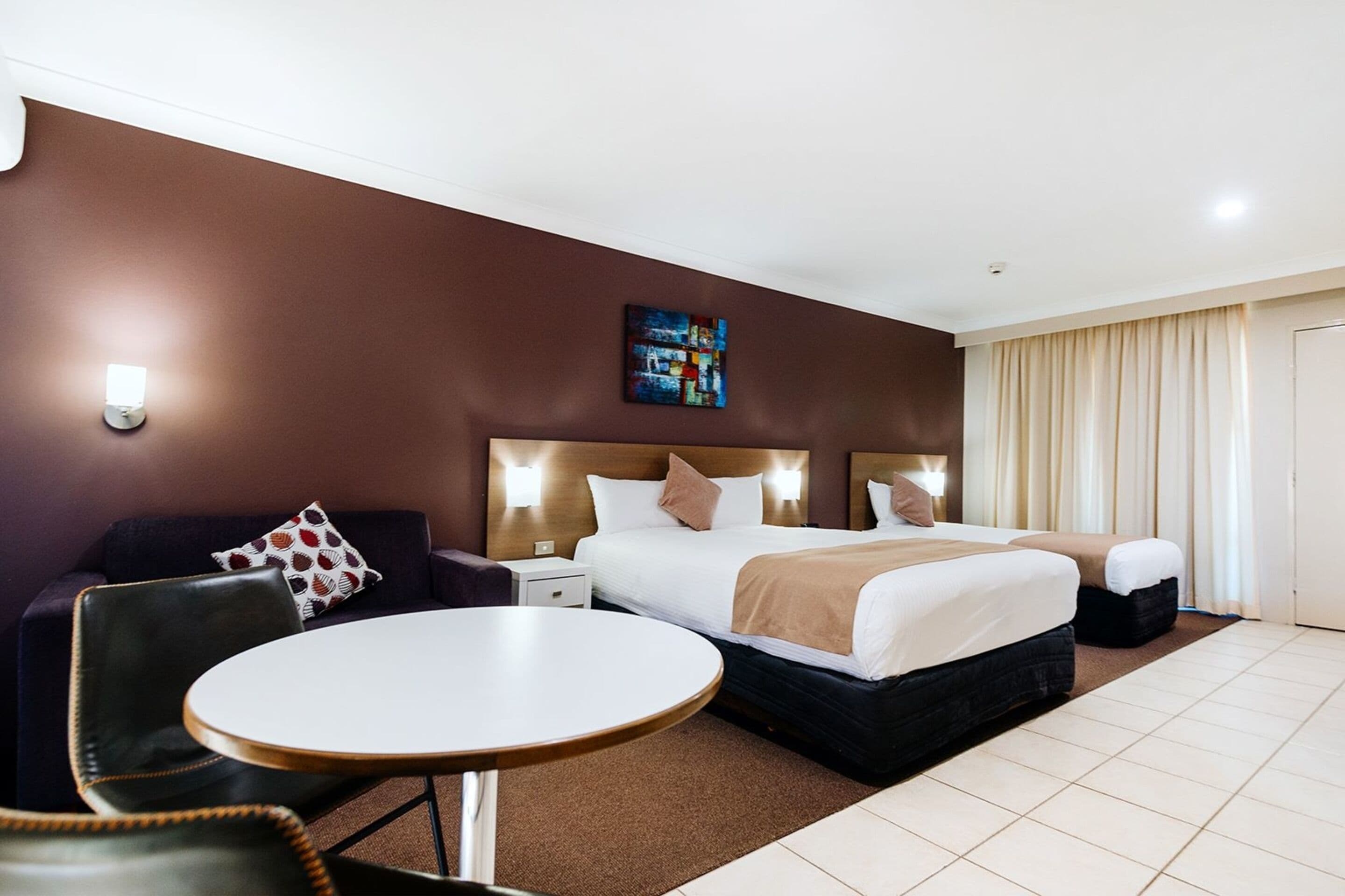 Ein Hotelzimmer mit einem großen Bett, einem runden Tisch, einer Couch und einem Gemälde an der Wand.