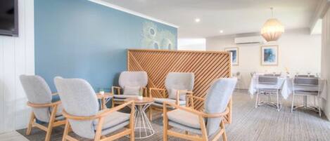 Una habitación de hotel moderna con una pared azul de acento, un panel de madera y un comedor con candelabro.