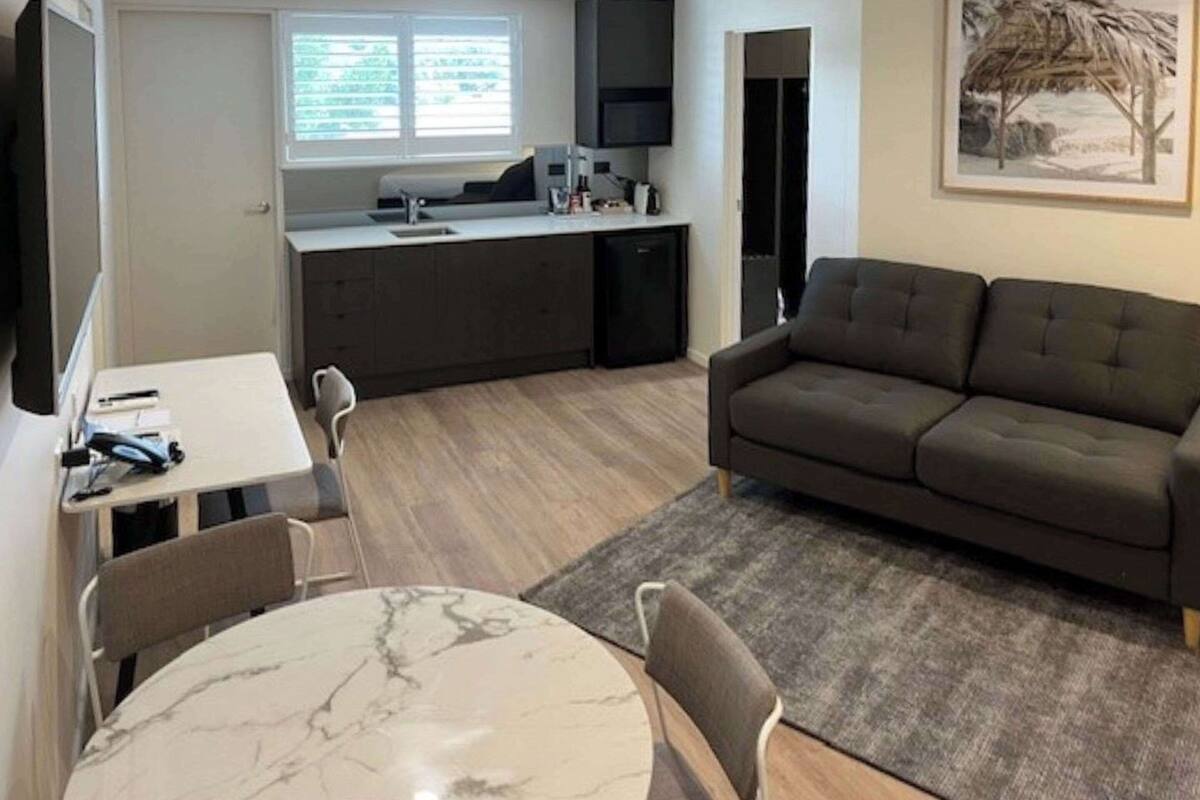 A compact living space with a dining area, a sofa, a kitchen, and a window.
