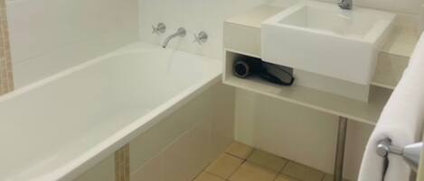 Un baño con bañera, lavabo, espejo y ventana.
