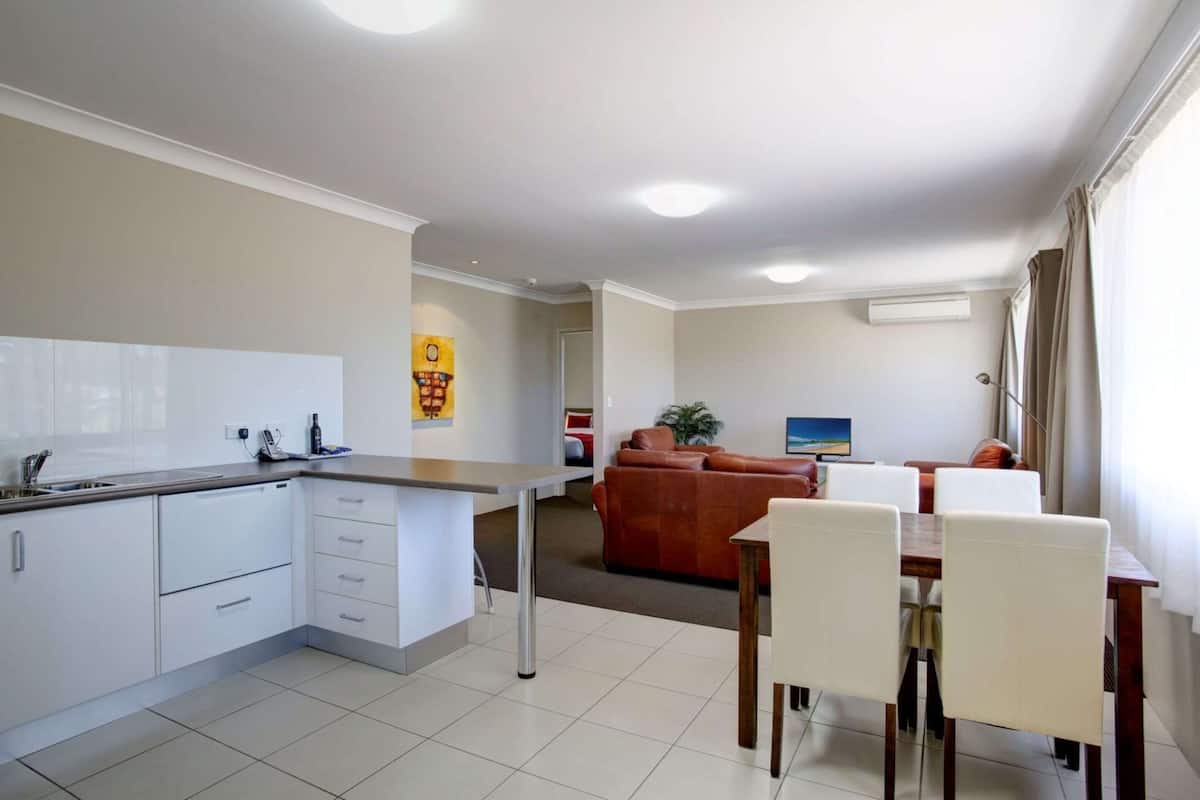 A modern kitchen with white cabinets and a dining area with a table and chairs.