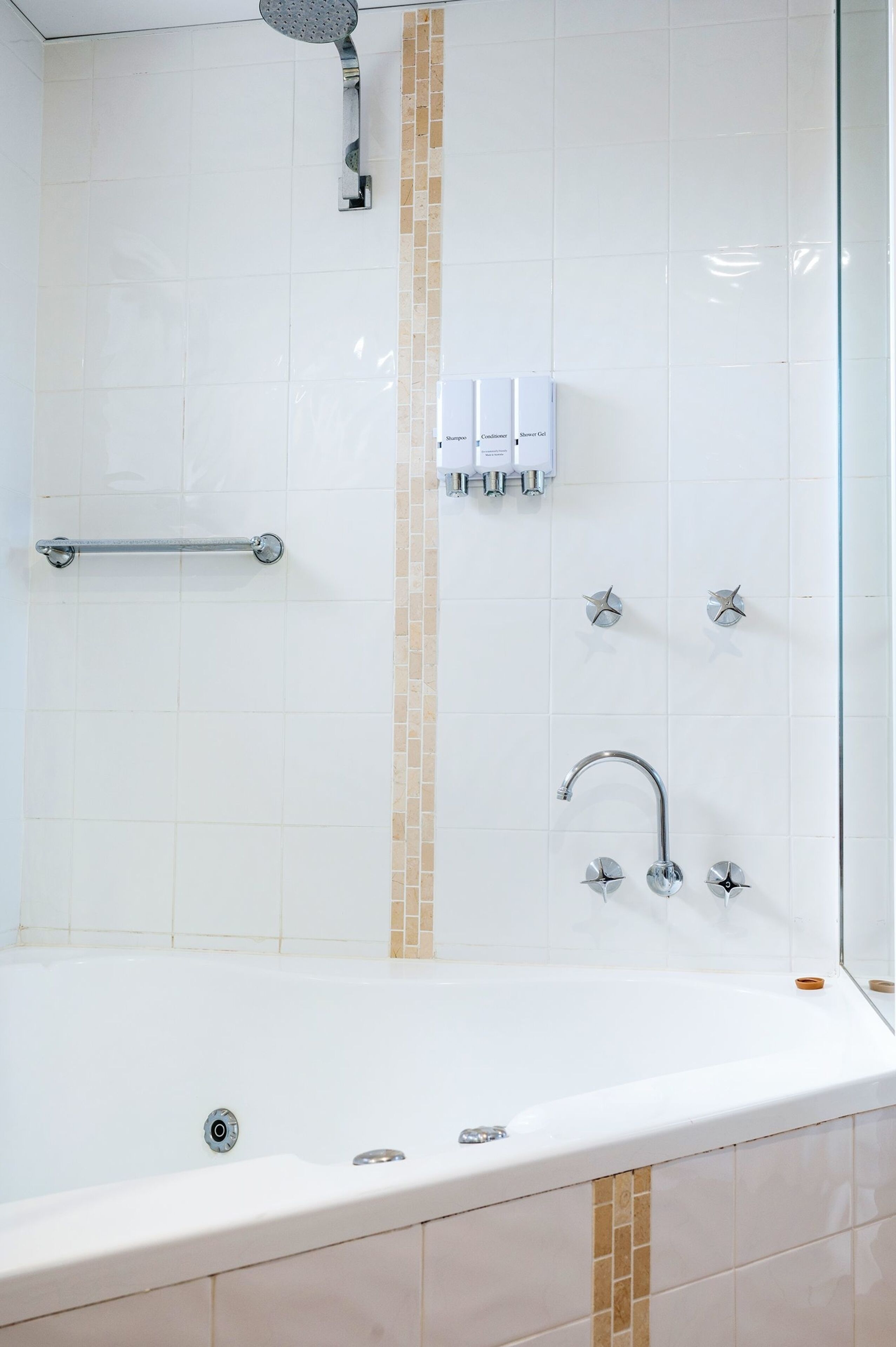 A modern bathroom with a bathtub, a handheld showerhead, a handheld shower, and a towel rack.