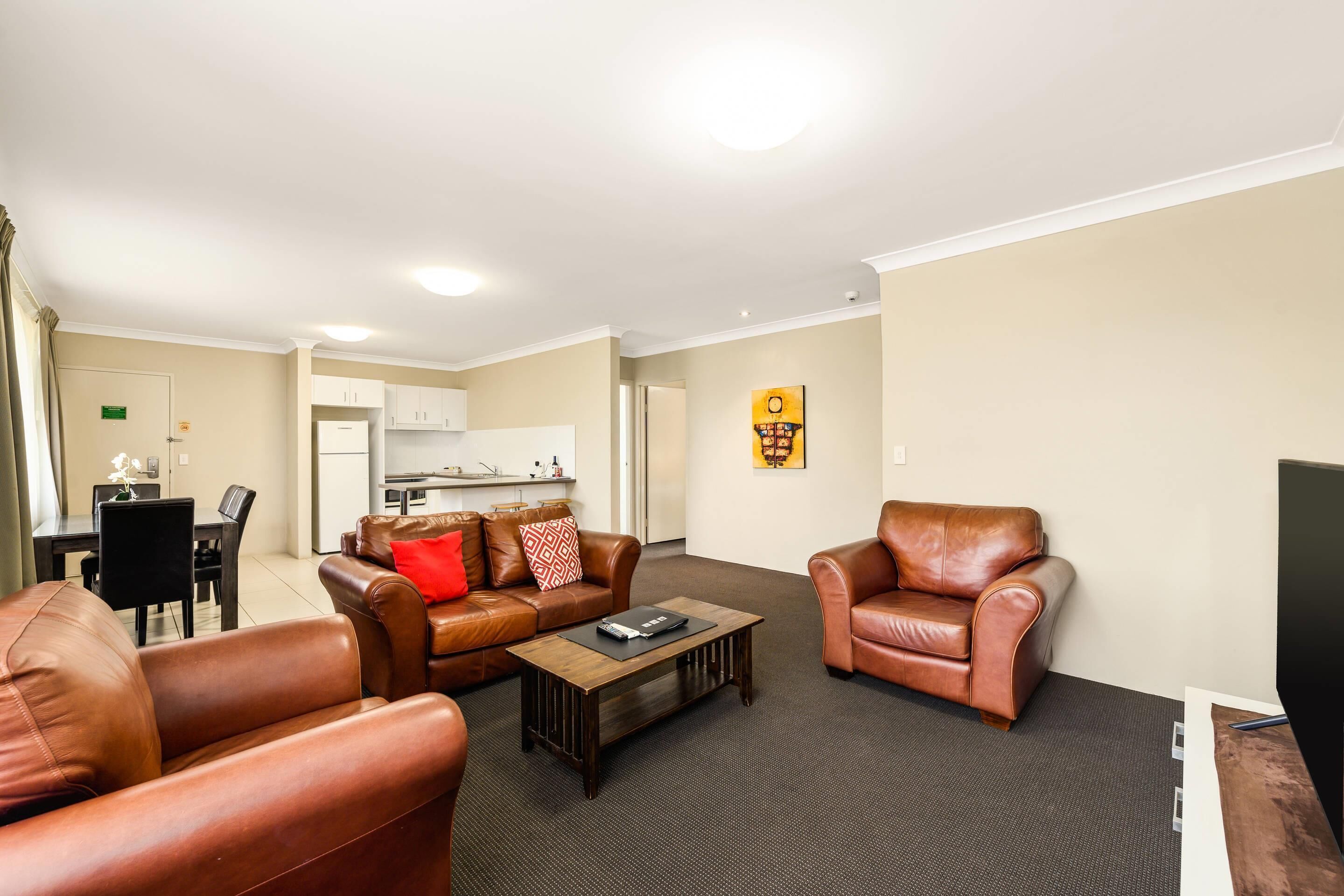A living room with leather sofas, a coffee table, and a television.