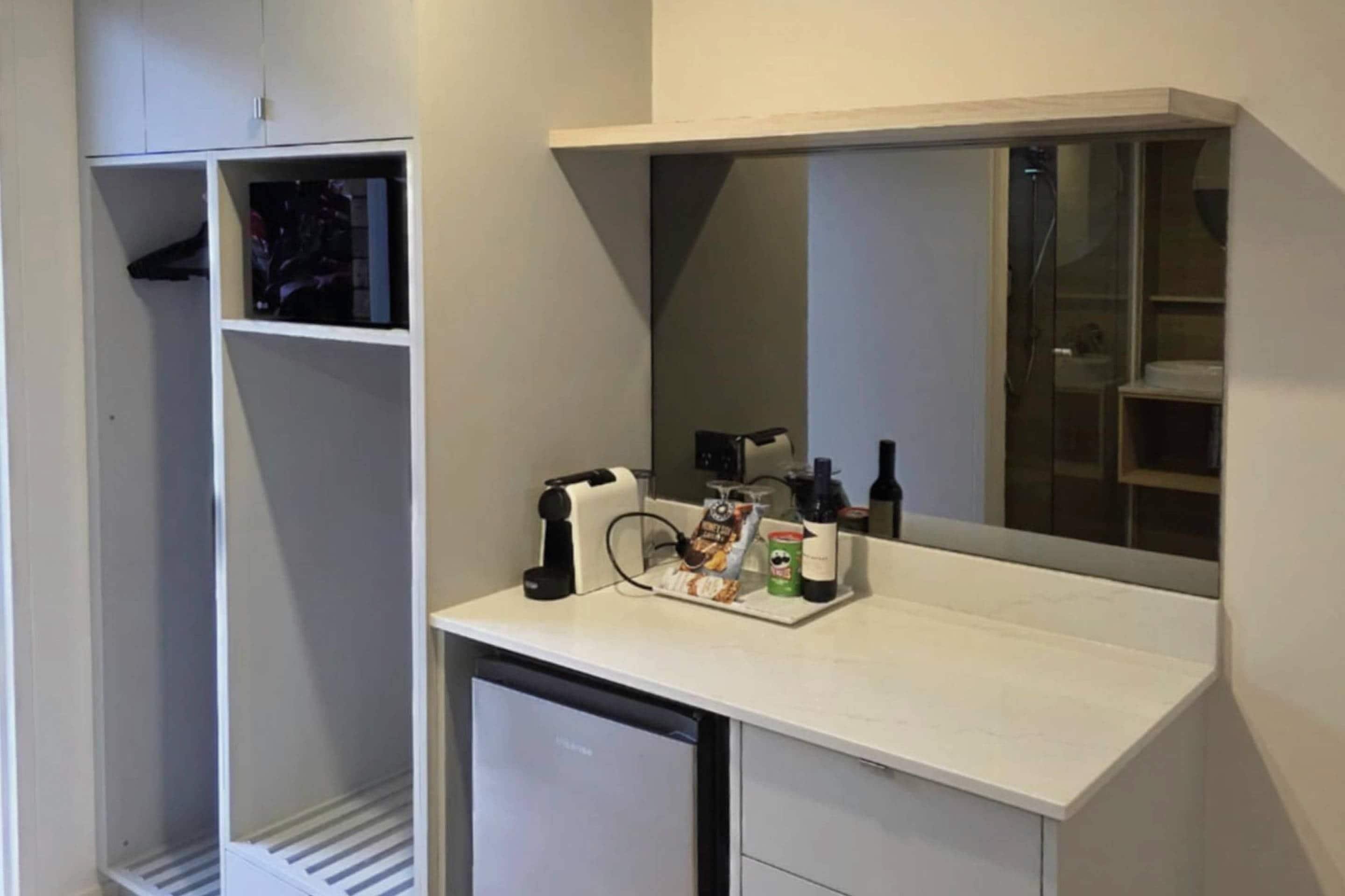 Ein kleines Badezimmer mit einem Waschtisch, einem Spiegel und einem Stauraumschrank.
