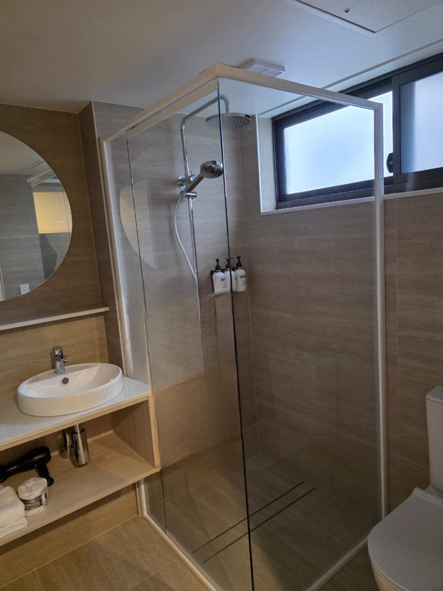 A modern bathroom with a glass-enclosed shower, a sink, and a toilet.