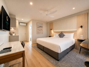 Una habitación de hotel moderna con cama, mesitas de noche, escritorio y televisión.