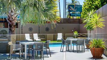 An outdoor patio area with tables and chairs, a swimming pool, and a sign for Quality Inn City Centre.