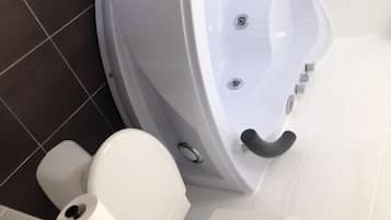 Une salle de bain moderne avec une baignoire blanche, des toilettes et un bidet.