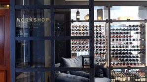 A modern interior with a kitchenette labeled 'WORKSHOP KITCHEN' and a wine rack filled with bottles. - Powerhouse Hotel Tamworth by Rydges (Tamworth)