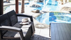 A poolside area with wicker furniture, a hat, and a table. - Powerhouse Hotel Tamworth by Rydges (Tamworth)