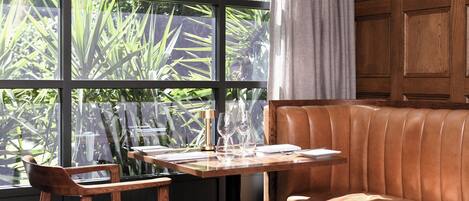 A cozy seating area with a leather couch and a wooden table set with glasses and a menu.