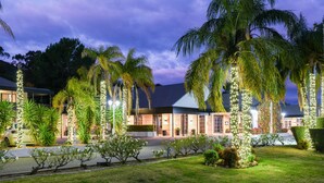 A hotel with a modern design, featuring a well-maintained garden with palm trees and other greenery. - Powerhouse Hotel Tamworth by Rydges (Tamworth)