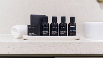Un meuble-lavabo de salle de bain avec un ensemble de produits de toilette comprenant un savon, un gel douche, un shampooing, un après-shampooing et une lotion pour le corps.
