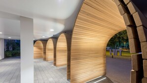 A modern building with wooden paneling and a series of arches. - NH Eindhoven Conference Centre Koningshof (Veldhoven)