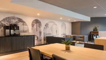 A modern hotel lobby with a wooden reception desk, seating area, and a mural on the wall.
