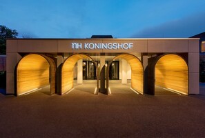 The exterior of NH Koningshof hotel with a modern design, featuring three large arched entrances and a prominent sign. - NH Eindhoven Conference Centre Koningshof (Veldhoven)