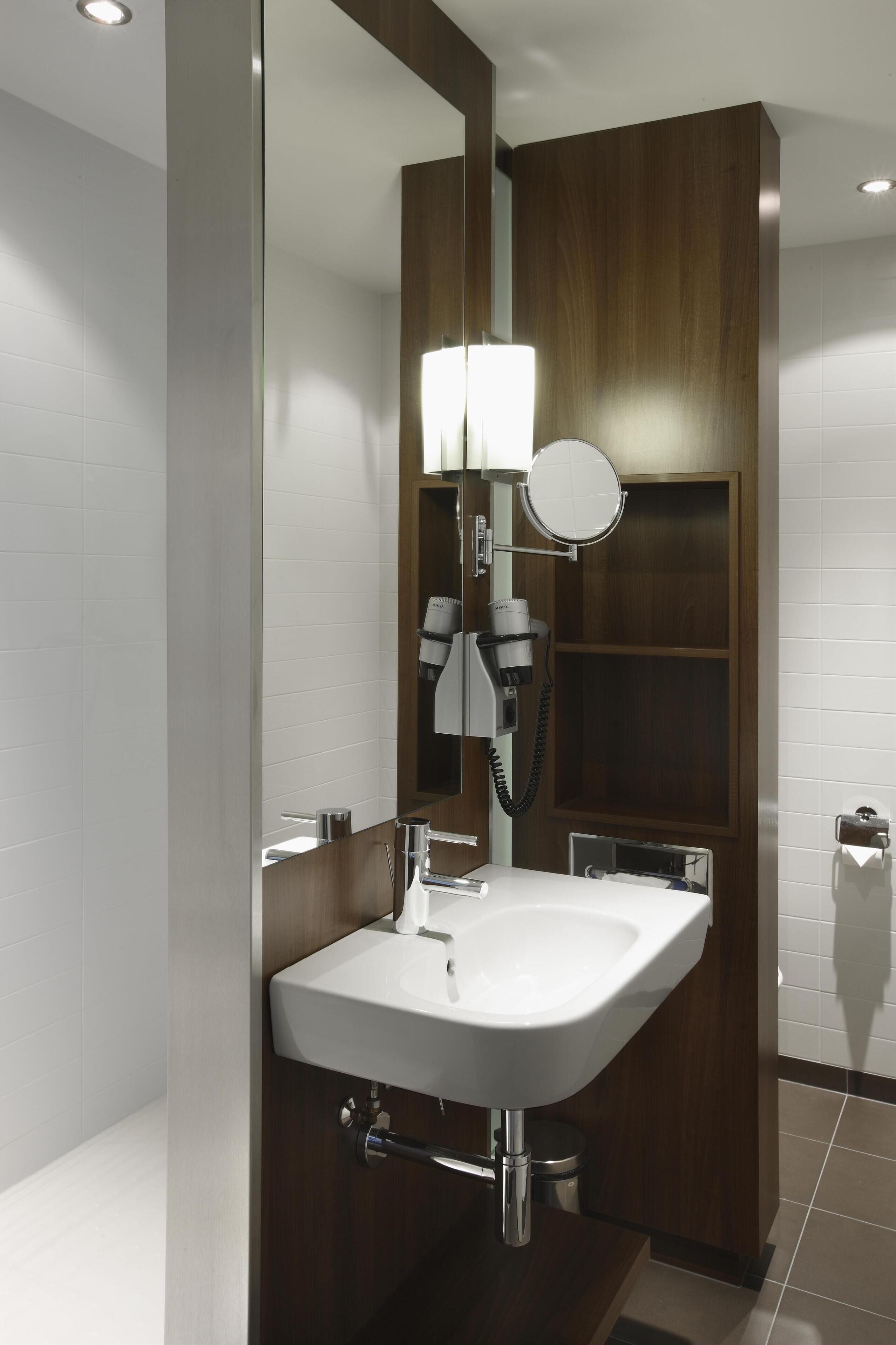 Une salle de bain moderne avec un lavabo blanc, un miroir et un sèche-cheveux.