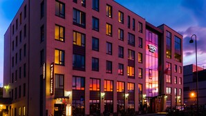 A multi-story hotel with a red brick facade, illuminated windows, and a prominent 'Thon Hotels' sign. - Thon Hotel Nordlys (Bodo)