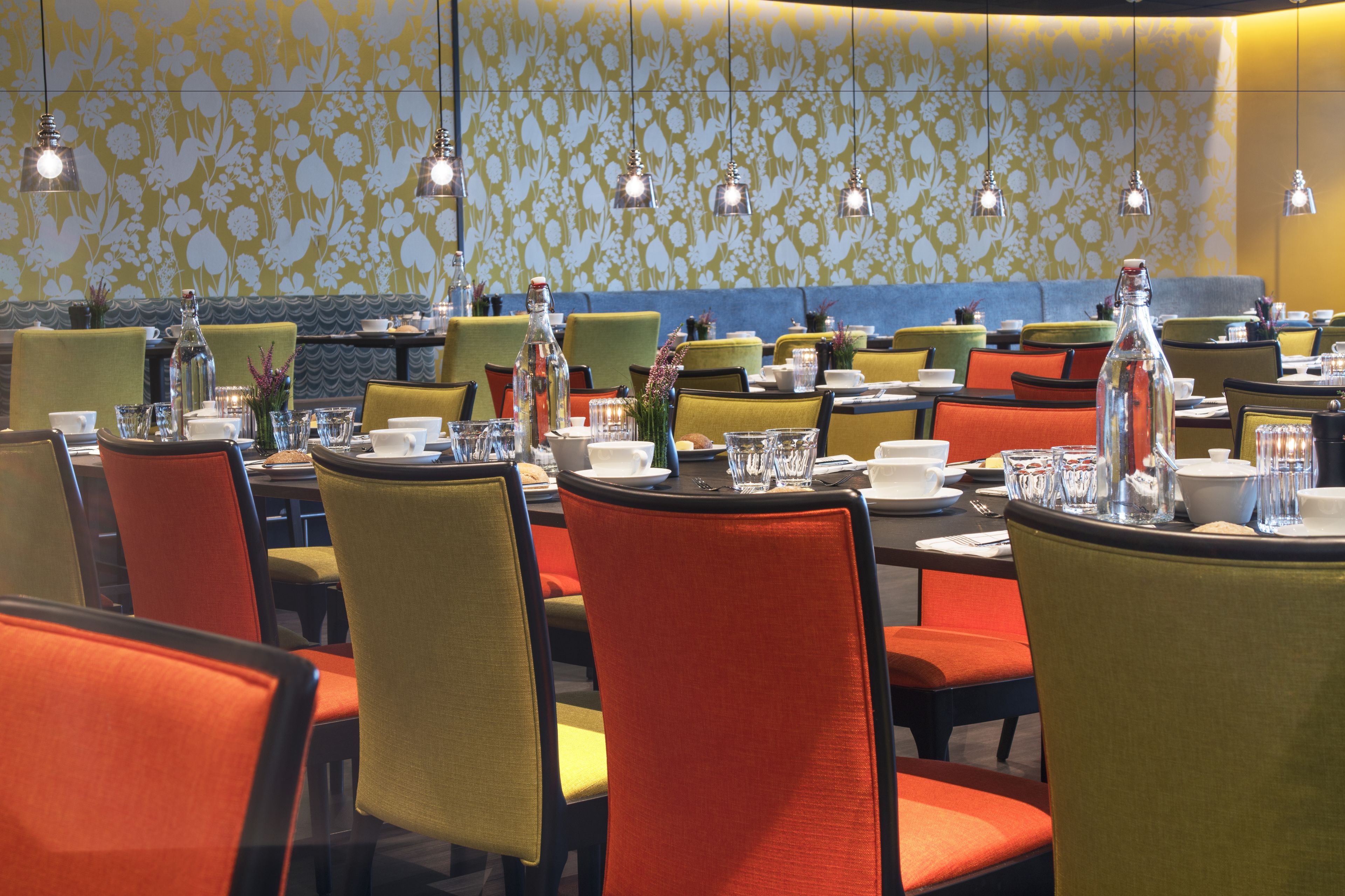 A restaurant with multiple tables and chairs, each set with plates, glasses, and cutlery.