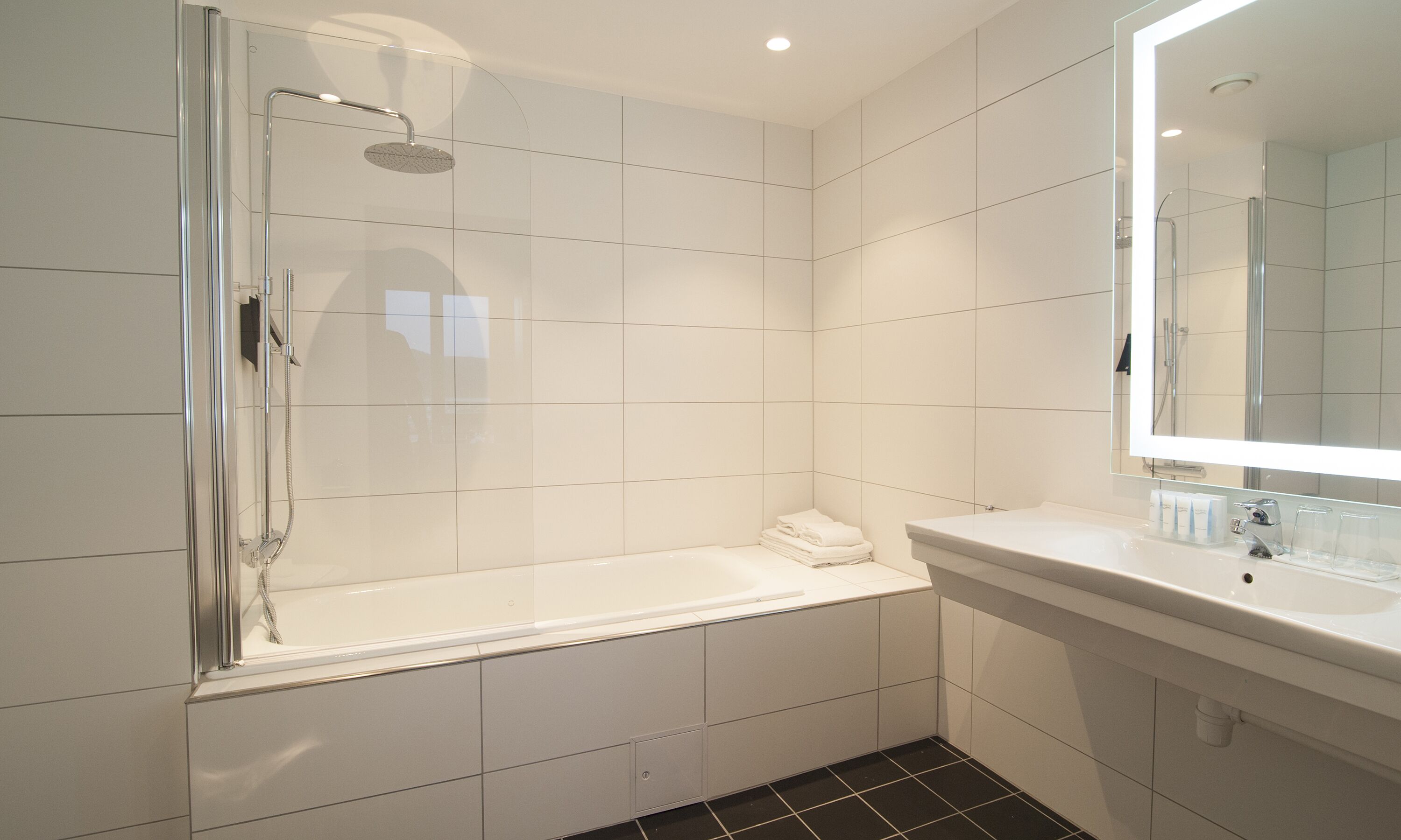 Une salle de bain moderne avec une douche à parois de verre, une baignoire blanche et un meuble-lavabo avec un miroir.
