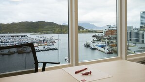 A view from a window overlooking a marina with boats, a dock, and buildings in the background. - Thon Hotel Nordlys (Bodo)