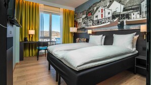 A hotel room with a bed, desk, chair, and a large window with curtains. - Thon Hotel Nordlys (Bodo)