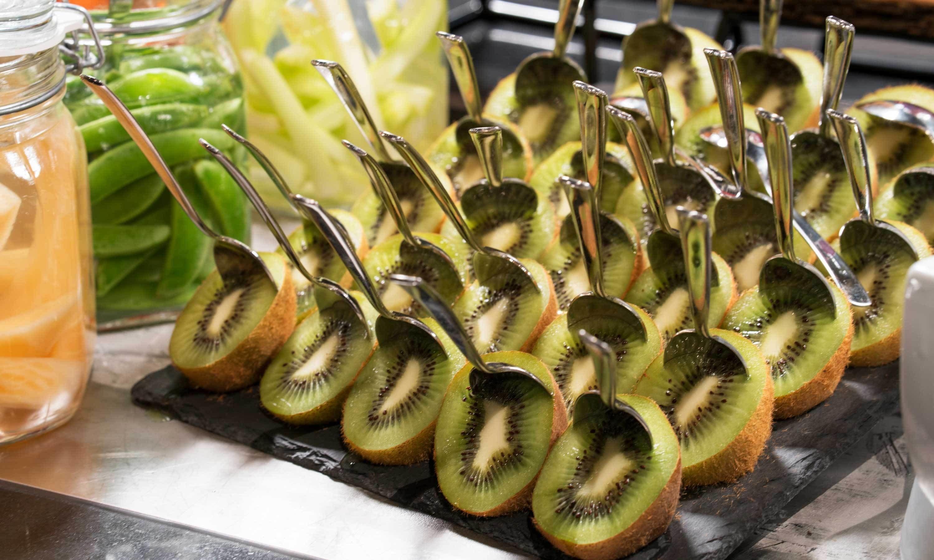 A tray of sliced kiwi arranged on a black slate board.