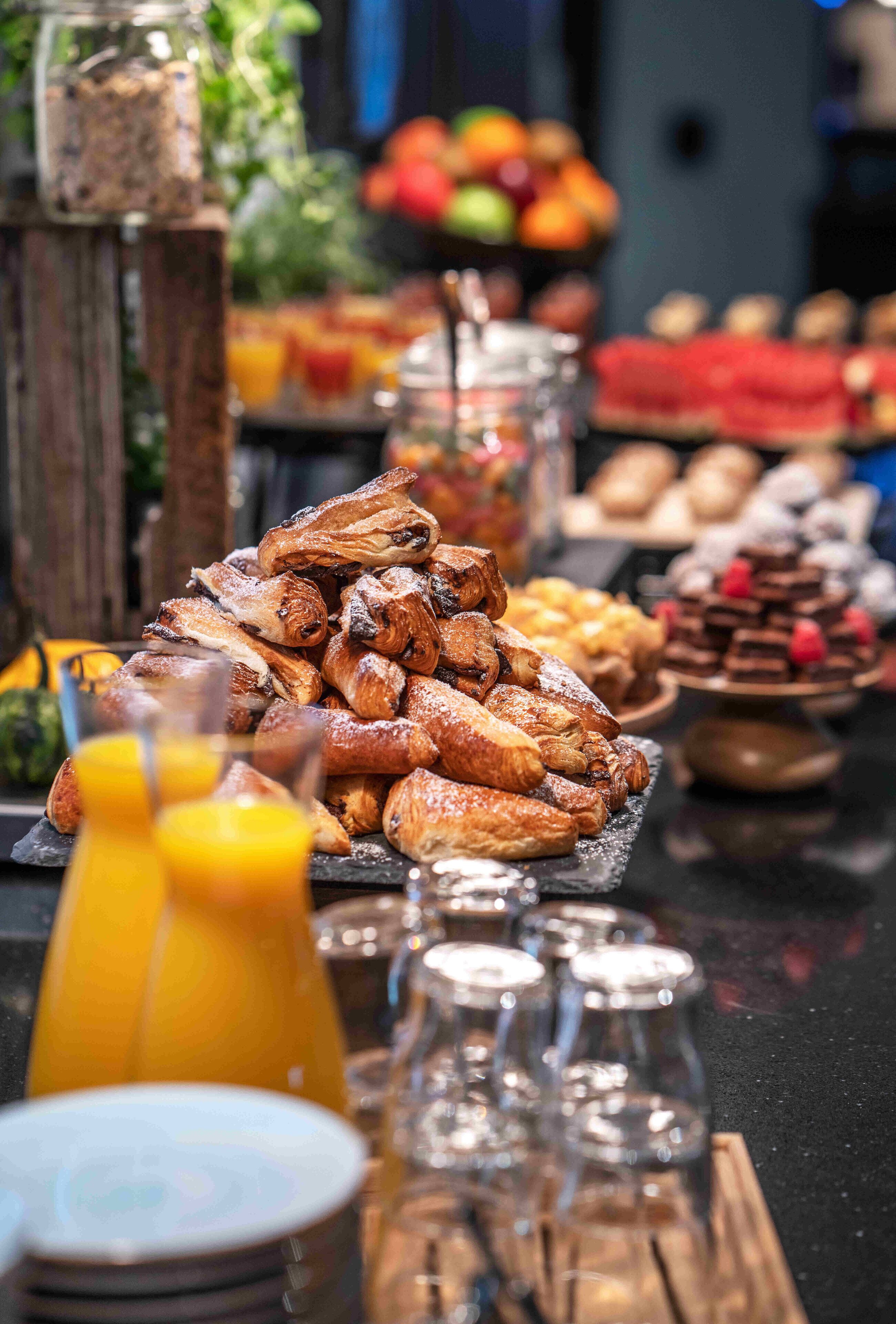 Un bufé con diversas opciones de pastelería y postres, como cruasanes y tartaletas de chocolate.