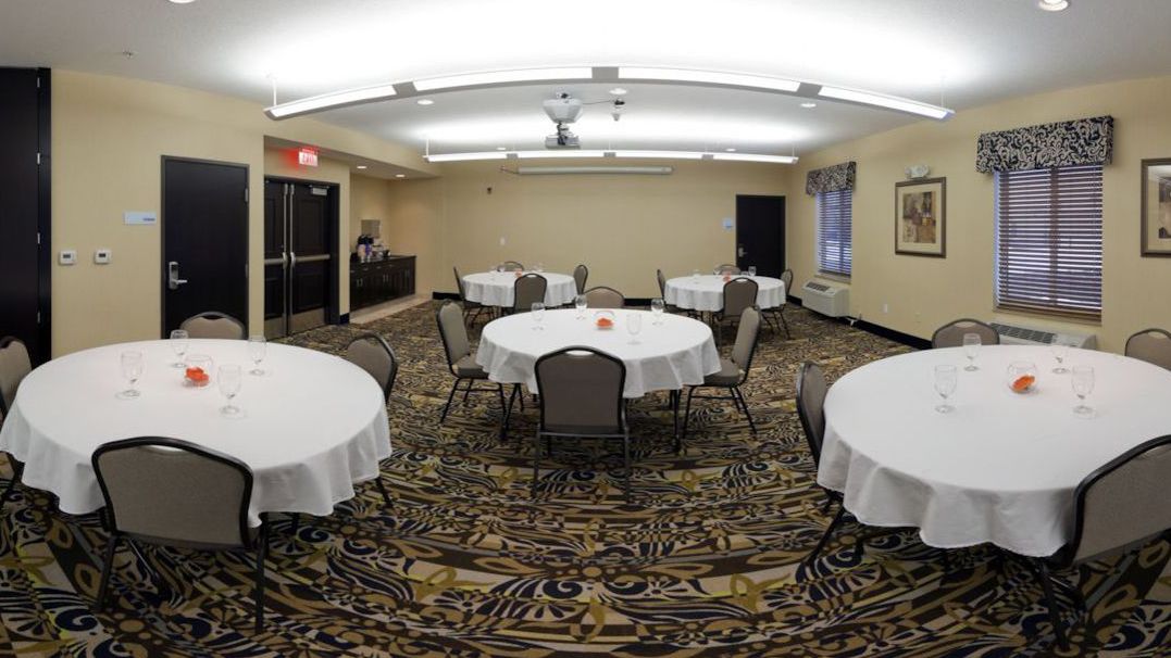 A conference room with round tables, chairs, and a patterned carpet.