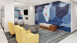 Un hall d’entrée avec un espace salon, une cheminée et une grande carte murale.