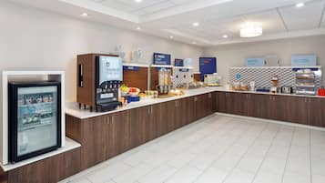 Un espace moderne dédié au petit-déjeuner, avec un buffet où les clients peuvent se servir eux-mêmes, proposant notamment des fruits, des céréales et des boissons chaudes.