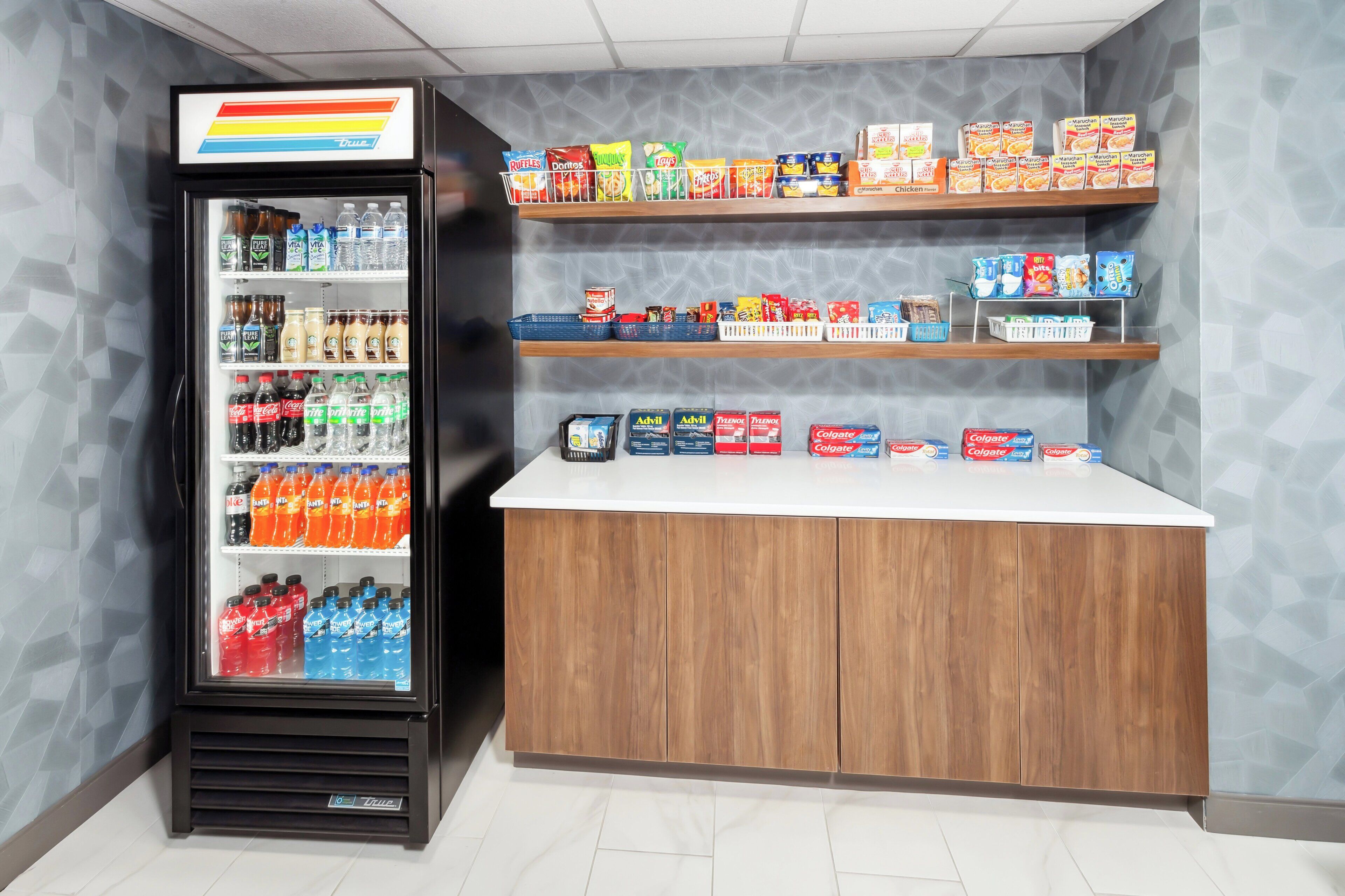 A vending machine stocked with beverages and snacks, a wooden counter, and shelves with various food items.