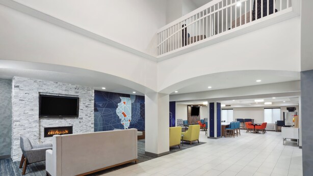 Un hall d’entrée spacieux au design moderne, comprenant un coin salon, une cheminée et un espace repas avec des tables et des chaises.