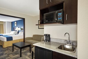 A compact hotel room with a kitchenette, including a microwave, coffee maker, sink, and a small dining table. - Holiday Inn Express & Suites Pekin (Peoria Area) by IHG (Pekin)