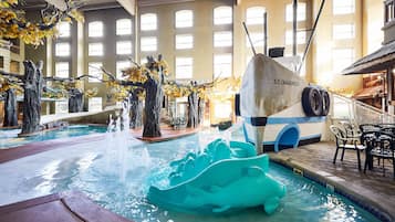 An indoor pool area with a boat-shaped water feature, seating, and a view of the interior.