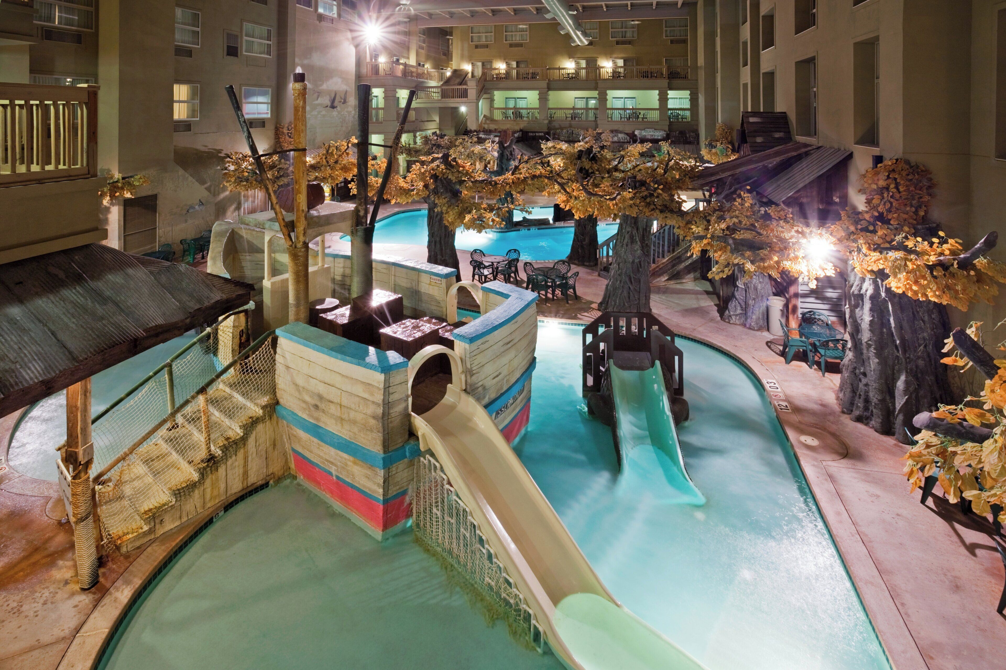 An indoor water park with slides, a pool, and artificial trees.