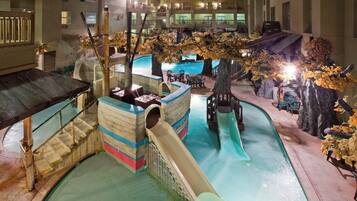 An indoor water park with slides, a pool, and artificial trees.