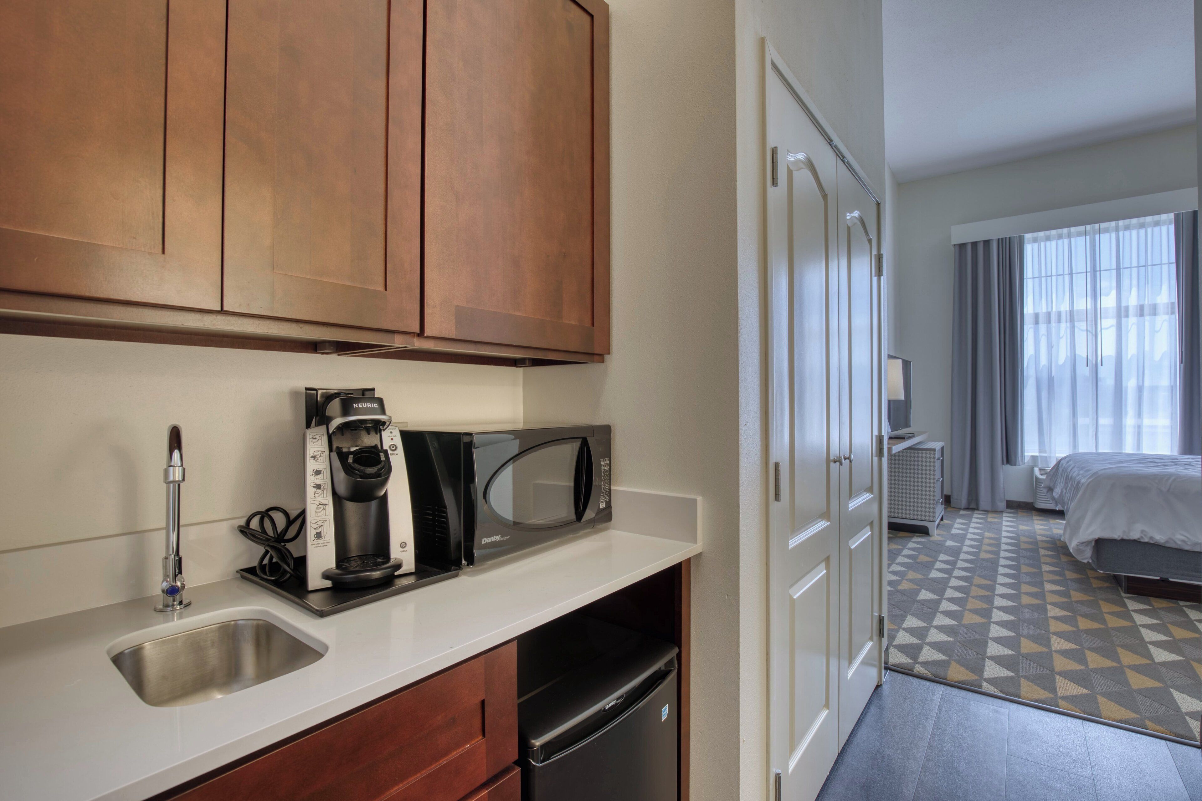 Quarto de hotel com cozinha compacta, cama e banheiro.