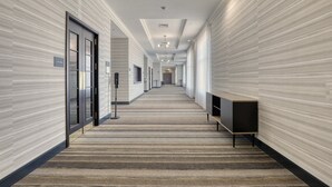 A long, narrow hotel corridor with a patterned carpet, a bench, and a door labeled "Exit."