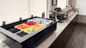 A buffet with various fruits and yogurt containers.