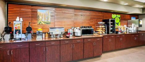 A hotel reception area with a long counter, various appliances, and a wooden wall with a mural.