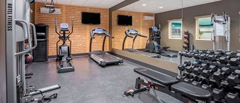 A hotel fitness center with treadmills, weight machines, and dumbbells.